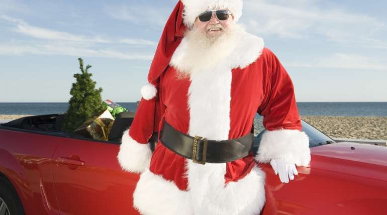 santa claus stands by red convertible