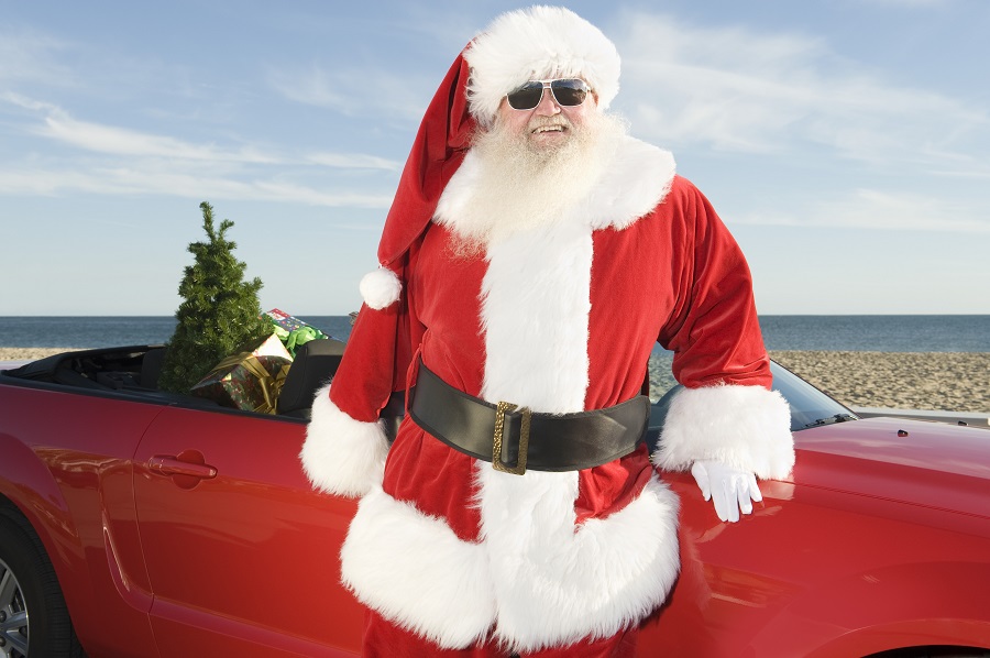 santa claus stands by red convertible